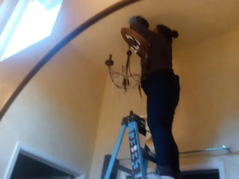 Electrician installing a chandelier in a West Salem residence